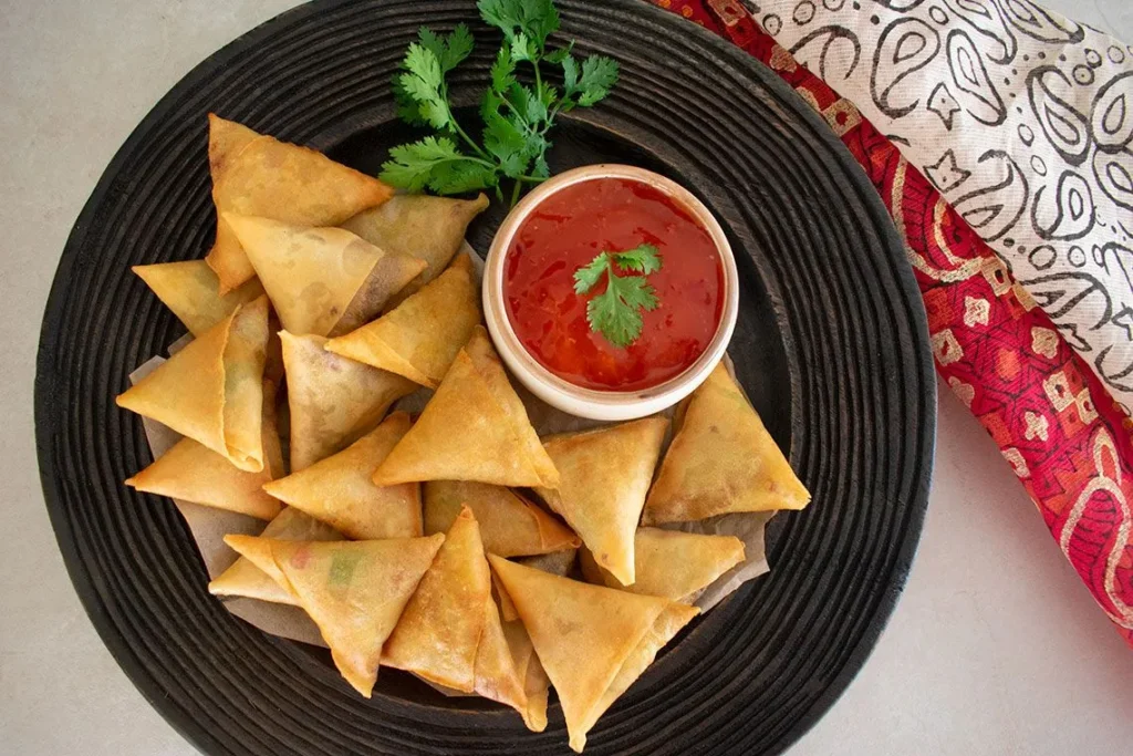 Close-up of crispy samosas and pakoras as finger foods at a corporate event. Close-up of crispy samosas and pakoras as finger foods at a corporate event.